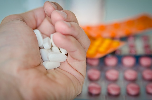 mão segurando medicamentos antidepressivos, com outros ao fundo