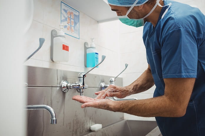 médico de touca e máscara lavando as mãos para evitar contaminação pelo coronavírus