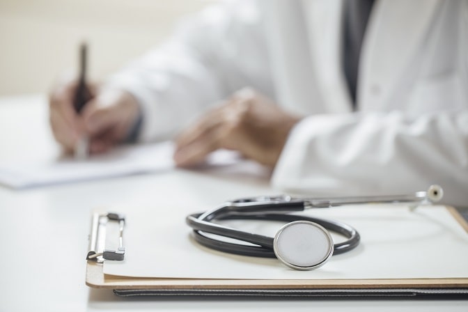 mãos de médico preenchendo prescrição para paciente com osteoartrite de mãos
