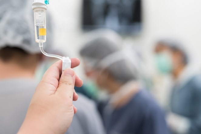 mão regulando via venosa de paciente internado em UTI com Covid-19