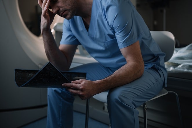 médico com burnout, sentado, após diagnóstico de covid-19 de paciente